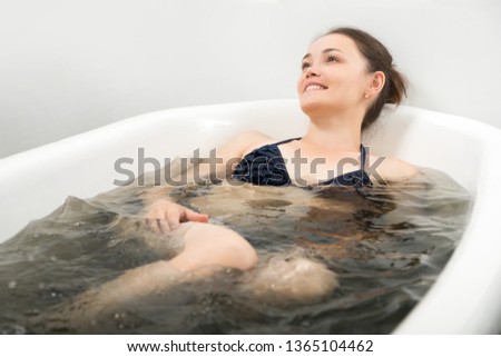 the woman in a bathing suit lies in bromine - an iodic bathtub