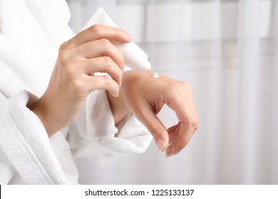 Woman In Bathrobe Applying Moisturizing Hand Cream, Closeup. Winter Skin Care Cosmetic