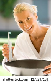 Woman In Bathrobe Brushing Teeth With Electric Toothbrush At Camera