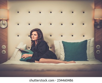 Woman In Bathrobe Lying On A Bed With Tablet Pc