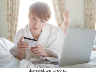 Woman in a bathrobe paying online with a credit card