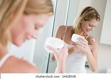 Woman In Bathroom Applying Lotion Smiling