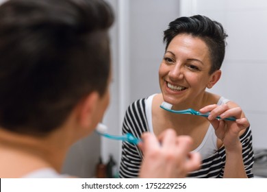 Woman In Bathroom Brushing Her Teeth