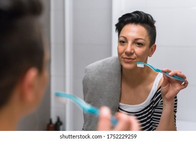 Woman In Bathroom Brushing Her Teeth