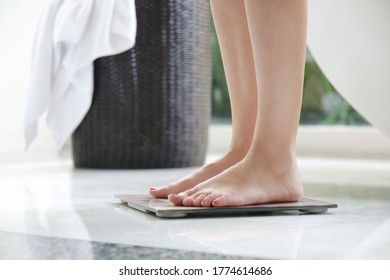 Mujer en el baño de pie en la escala de peso digital, concepto de dieta.