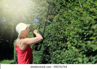 A Woman With Battery Driven Hedge Trimmer