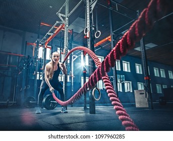 Woman with battle rope battle ropes exercise in the fitness gym. CrossFit concept. gym, sport, rope, training, athlete, workout, exercises concept