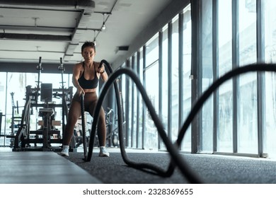 Woman with battle rope battle ropes exercise in the fitness gym. gym, sport, rope, training, athlete, workout, exercises concept - Powered by Shutterstock