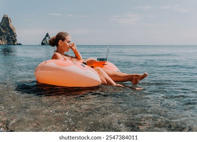 Woman, Beach, Laptop - Woman relaxing on an inflatable raft in the ocean, working on her laptop, enjoying the summer day. - Powered by Shutterstock