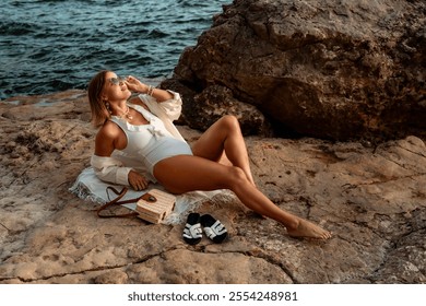 Woman, Beach, Relaxing - Woman in white swimsuit relaxing on a rocky beach near the sea. - Powered by Shutterstock