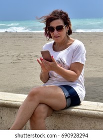 Woman At Beach Using Her Cell Phone