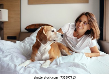 Woman and beagle dog wake up and meet new day in bed