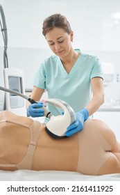 Woman beautician burning fat in patient back with vela shape
