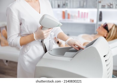 Woman beautician using laser epilation machine in beauty salon