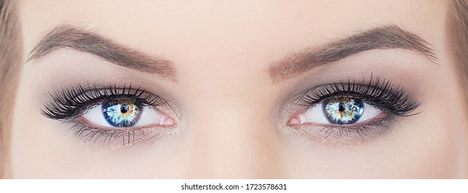 woman with beautiful blue eyes with long eyelashes. hypnotic look closeup. smoky eyes make up