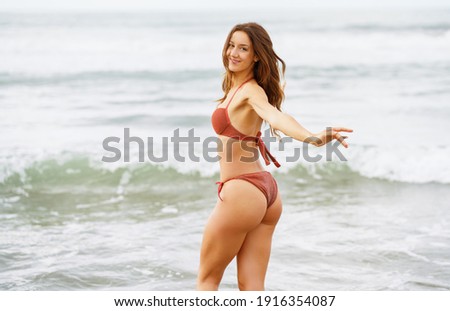 Woman with beautiful body enjoying her bath on the beach wearing red bikini