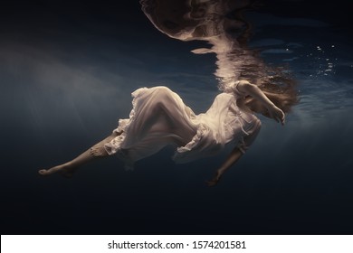 Woman in a beautiful dress swims underwater