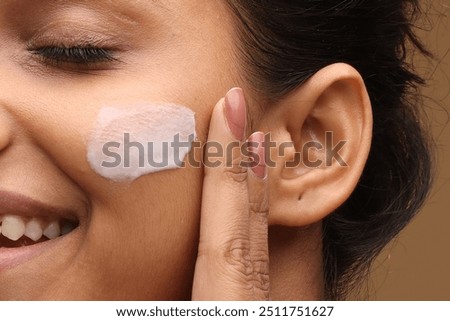 Woman with beautiful face touching healthy facial skin portrait. Beauty close up girl is applying a skincare product. Hydration. Cream smear.