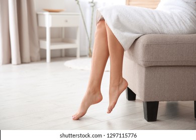 Woman With Beautiful Legs And Feet Sitting On Ottoman Indoors, Closeup With Space For Text. Spa Treatment