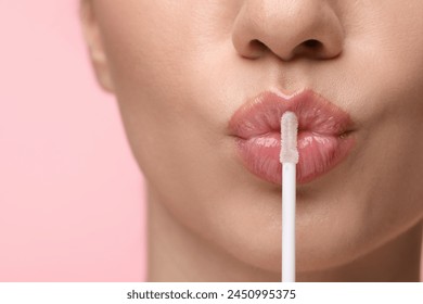 Woman with beautiful lip gloss and applicator on pink background, closeup - Powered by Shutterstock