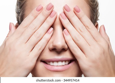 Woman with beautiful natural manicure closes eyes with her hands