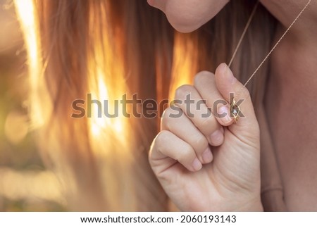 Woman with a Beautiful Pendant on her Neck in Mild Sunlight. Golden Chain with Little Precious Stone. Luxury Jewelry.