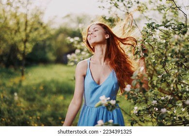 Woman with a beautiful smile with teeth and long hair flying hair spring dance into the sunset in the park near the flowering trees happiness, natural beauty and hair health - Powered by Shutterstock