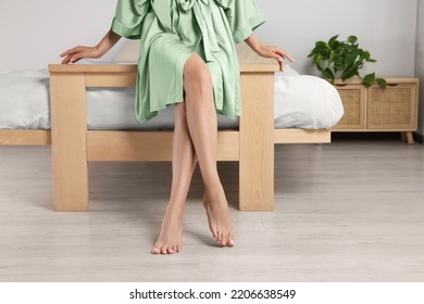 Woman With Beautiful Smooth Legs In Silk Robe Sitting On Bed At Home, Closeup