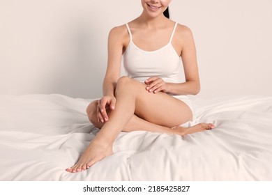 Woman With Beautiful Smooth Legs Sitting On Bed At Home, Closeup