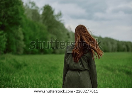 a woman with beautiful, well-groomed jumpy hair developing in the wind stands in a field