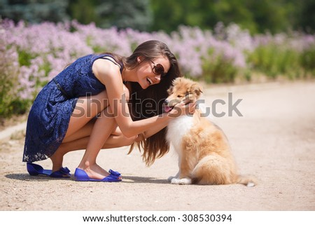 woman beautiful young happy with long dark hair in striped sweater holding collie dog. Young woman playing with Collie puppy outdoors in the park.