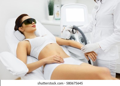 Woman Beauty. Beautician Doing Epilation On Beautiful Girl's Body In Medical Center. Female Receiving Laser Light Hair Removal Treatment For Hairless Smooth Skin At Cosmetology Salon. High Resolution