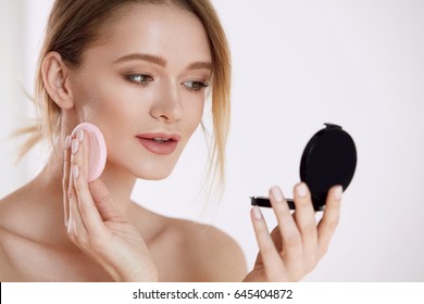 Woman Beauty Face. Closeup Of Beautiful Female With Cushion Puff And Mirror Applying Makeup Powder Foundation. Portrait Of Sexy Girl With Fresh Soft Skin Putting Cosmetic Product. High Resolution