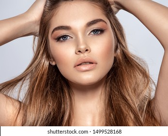 Woman with beauty long brown hair and natural makeup.  Beautiful face of an attractive  model with blue eyes. Closeup portrait of a caucasian female. Attractive fashion model.