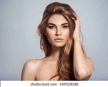 Woman with beauty long brown hair and natural makeup.  Beautiful face of an attractive  model with blue eyes. Closeup portrait of a caucasian female. Attractive fashion model.