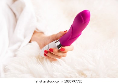 Woman in bedroom holding vibrator in hand