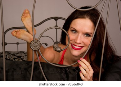 Woman In Bedroom Wrought Iron Headboard Laying On Bed 