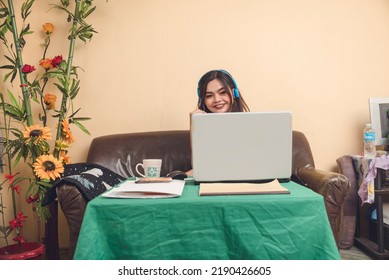 A Woman Behind Her Laptop. Body Does Not Show. Lady Sitting On A Couch While Peeking Above Her Laptop As If Beheaded.