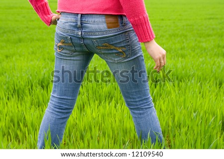 Woman from behind standing in grass, holding it. Copy space. Horizontal.