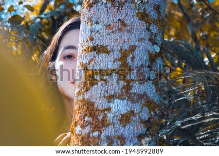 Woman behind white tree in forest