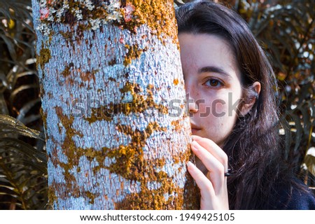 Woman behind white tree in forest