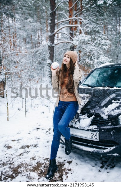 woman in beige clothes standing near the car in\
the winter snowy forest
