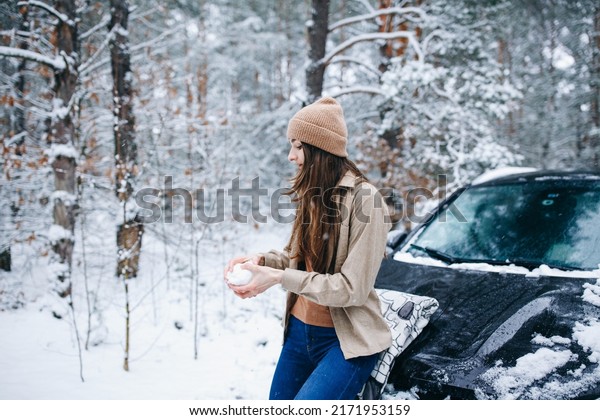 woman in beige clothes standing near the car in\
the winter snowy forest