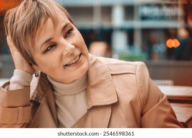 Woman in a beige coat enjoying a relaxed moment while sitting at a cafe in an urban area during the daytime - Powered by Shutterstock