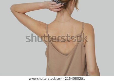 Woman in beige cotton camisole shirt, studio shot.