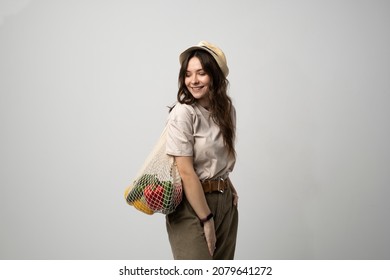 Woman In A Beige T-shirt And A Hat Holding Mesh Shopping Bag With Groceries. Conscious Consumption. Eco Trend. Zero Waste Concept. Girl Carry Bag Shopper.