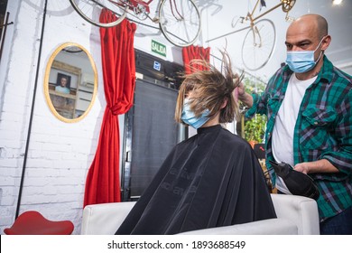 Woman Being Combed By Hairdresser With Spray And Blow Dryer In Front Of Mirror In Modern Retro Hair Salon