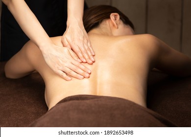 The woman is being massaged on her back.
