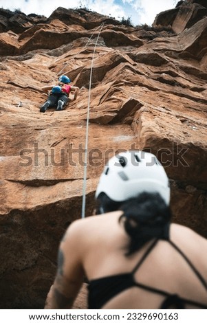 A woman is belaying a climber in La Mojarra climbing park at Mesa de los Santos, Santander. Colombia.
