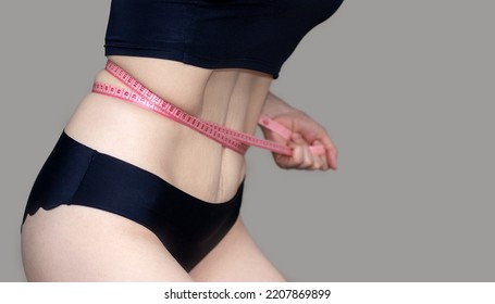 Woman Belly Abdomen Isolated On Gray Measuring Waist With Measure Tape Band Or Holding Tummy Fat With Hands.girl Doing Home Vacuum Exercise After Child Birth,recovery Fit Slim Weight Loss